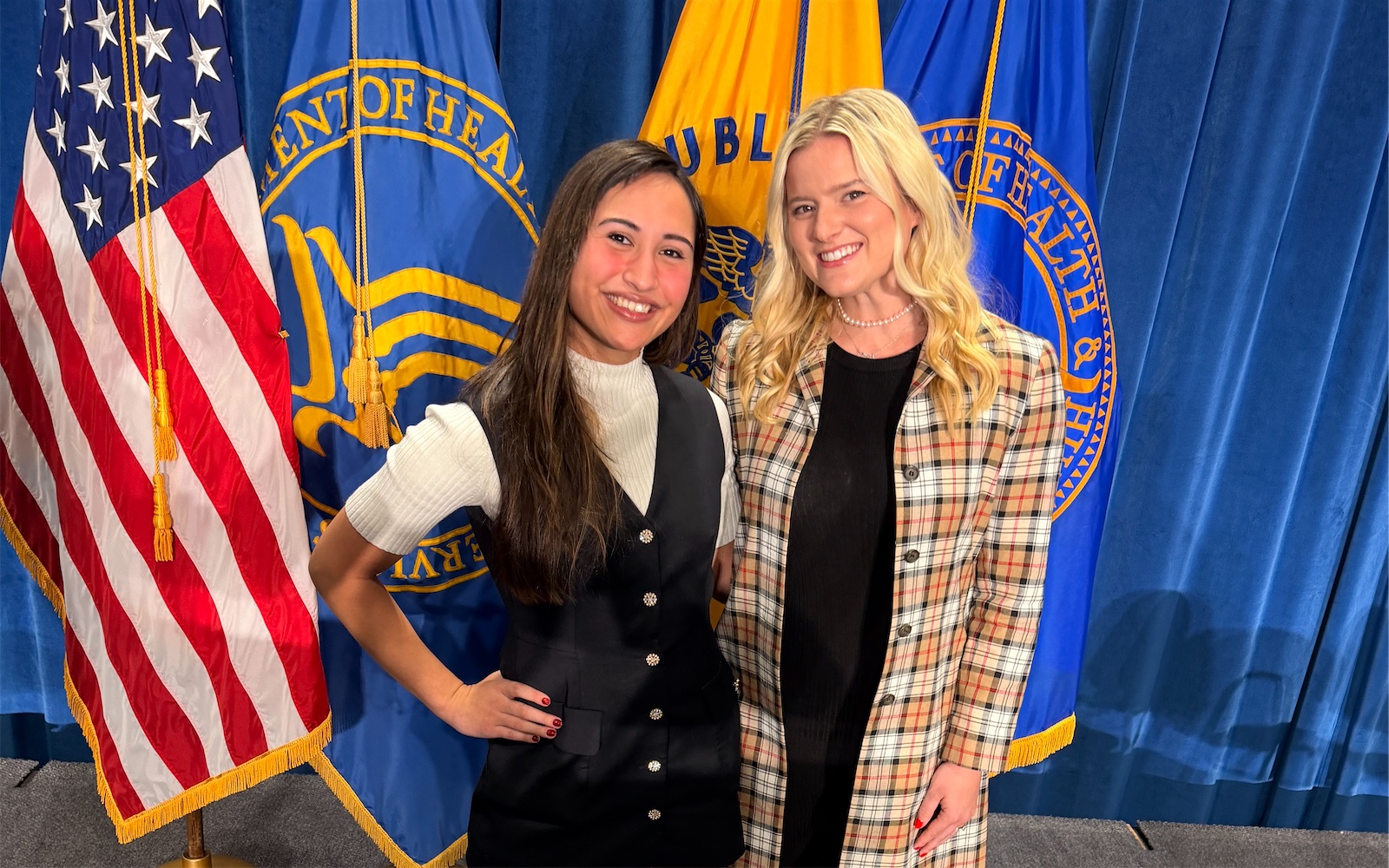 Daytona Everett with a colleague in front of the flags at the Department of Health and Human Services