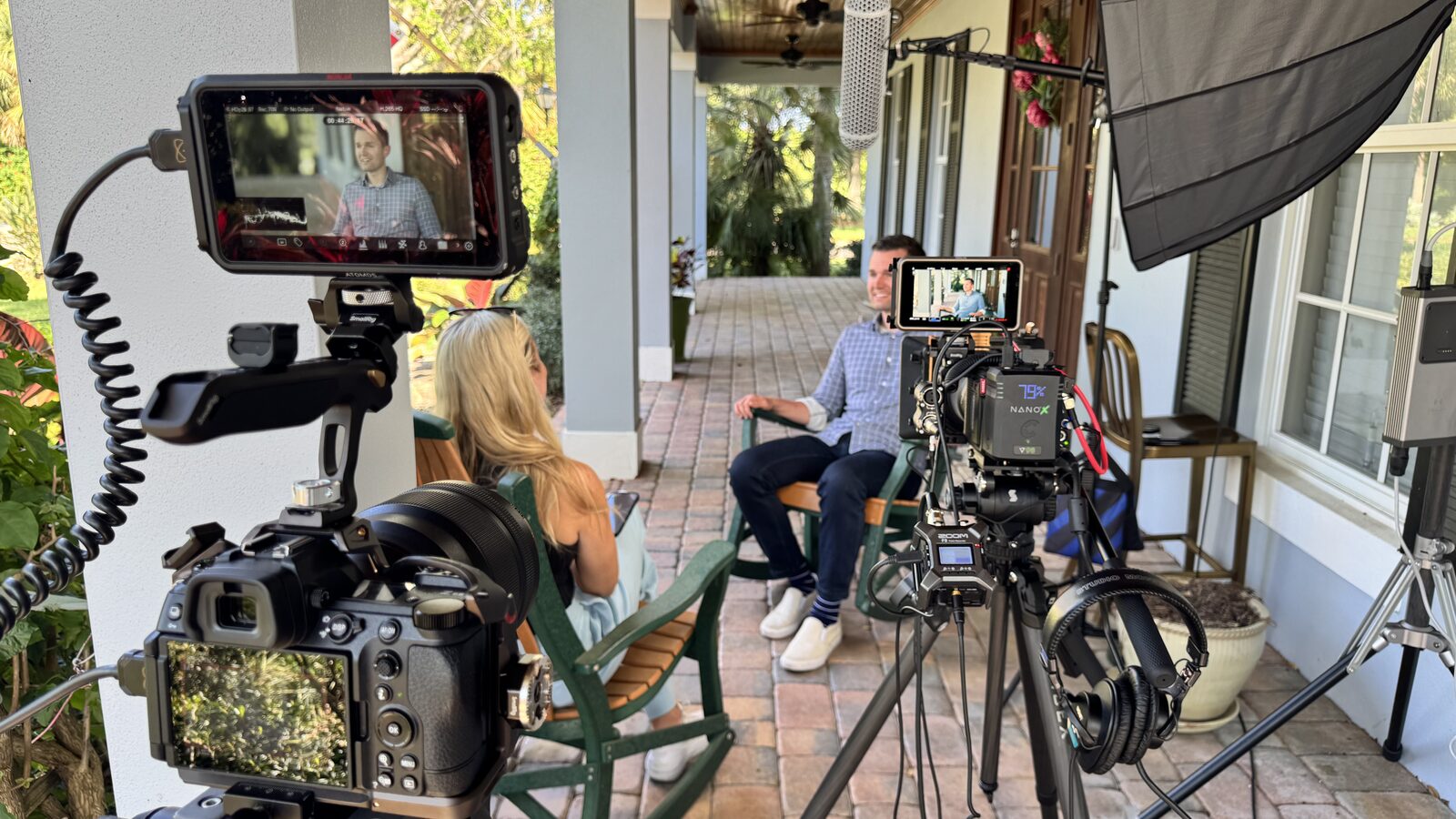Daytona Everett interviewing Mark on a porch, two cinema cameras and a boom mic framing the conversation