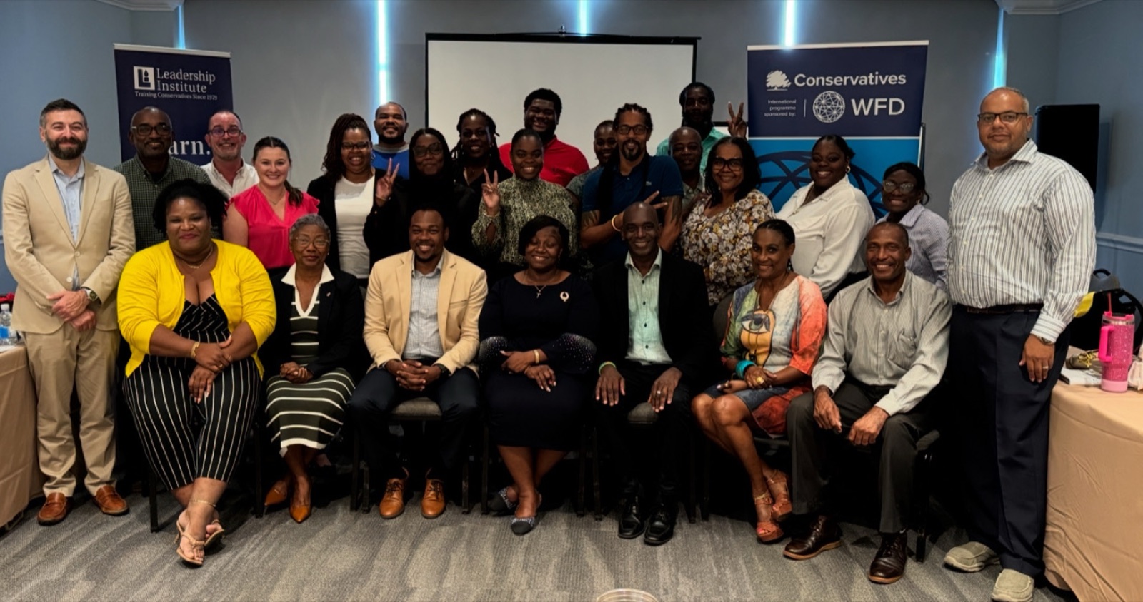 A training cohort of about thirty posed between Leadership Institute and Conservatives / WFD banners in a seminar room